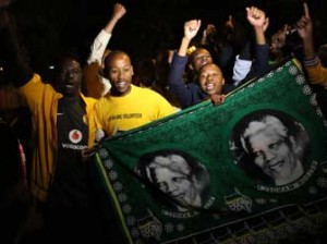 South Africans hold pictures of former South African president Nelson Mandela as they pay tribute following his death in Johannesburg on December 5, 2013. Mandela, the revered icon of the anti-apartheid struggle in South Africa and one of the towering political figures of the 20th century, has died aged 95. Mandela, who was elected South Africa's first black president after spending nearly three decades in prison, had been receiving treatment for a lung infection at his Johannesburg home since September, after three months in hospital in a critical state. AFP PHOTO