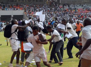 NIGERIA, Abuja : Job-seekers applying for work at the Nigerian immigration department scramble as their exam papers fly in the air, on the pitch of Abuja National Stadium, on March 15, 2014. AFP PHOTO