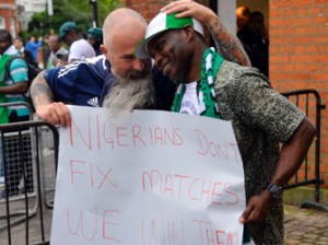 THE PATRIOT . . . A Nigeria fan holding a placard is embraced by a Scotland fan before kick off