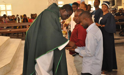 REV.FR. RAPH ASIKA (L),PRESENTING HOLY COMMUNION ON PARISHIONERS HAND DUE TO FEAR OF EBOLA SANITISER ON THE HANDS OF ST PAUL CATHOLIC CHURCH GWAGWALADA ON SUNDAY (10/8/14)./NAN