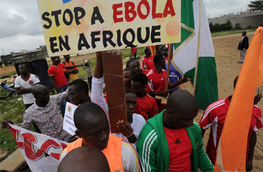 Players of the ''FC Gberedou Abobo" football team poses with a sign reading ''Stop ebola in Africa" prior to a football tournament gathering youth from Guinea near the Koumassi sports center in Abidjan on August 10, 2014. West Africa was counting the cost of measures to contain the deadly Ebola epidemic on August 10, as unprecedented restrictions caused snarled transport, food shortages and soaring prices. AFP PHOTO
