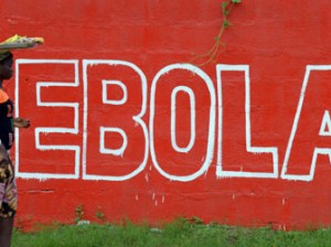 A seller of bananas walks past a slogan painted on a wall reading "Ebola" in Monrovia on August 31, 2014. Liberia on August 30, 2014 said it would deny permission for any crew to disembark from ships at the country's four seaports until the Ebola epidemic ravaging west Africa was under control. AFP PHOTO