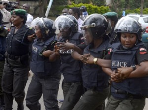 Police officers holds arms to block supporters of 219 schoolgirls kidnapped by Boko Haram militants from marching on the president's official residence in Abuja on October 14, 2014. Some 276 girls were seized from their dormitories at the Government Girls Secondary School in the remote town of Chibok in Borno state, northeastern Nigeria, on the night of April 14. AFP PHOTO