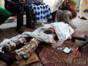 Relatives sit around one of the victims of twin suicide blasts at Kano central mosque in the accident and emergency ward of the Nassarawa Specilist Hospital in northern Nigeria's largest city of Kano on November 28, 2014. At least 120 people were killed and 270 others wounded when two suicide bombers blew themselves up and gunmen opened fire during weekly prayers at the mosque, a week after the emir of Kano, Muhammad Sanusi II, of one of Nigeria's top Islamic leaders called on northerners to defend themselves against Boko Haram Islamists tha have been carrying deadly attacks and seizure of territory in the northeast. AFP PHOTO