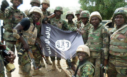 A handout picture from the Nigerian military taken on February 26, 2015 shows troops posing with a flag of Boko Haram after dismantling a Boko Haram camp along Djimitillo Damaturu road, Yobe State in northeastern Nigeria, following fierce fighting that resulted in the capture of machine guns and rifles as well as the death of a number of the insurgents. Boko Haram has vowed to disrupt March 28 elections, which originally were planned for February 28 but rescheduled following security threat. AFP 