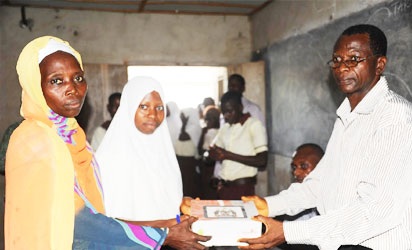 The   Principal  of Kuta Community  high School, Mr Asifat musibau (right), giving  a   Tablet of knowledge  (OPON IMO) to a student,  Lateef Muminat. With them is her   mother Mrs Lateef Silifat, during the distribution of Tablet of knowledge by the   State Government to students of Kuta Community  High school, Kuta,  State of Osun   