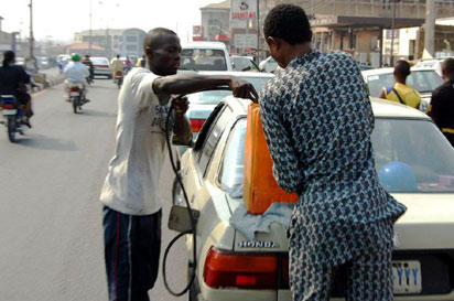 A motorist refueling his car at a black market