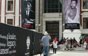 A man takes a picture of giant photographs of late South African president Nelson Mandela hanging on a facade of the South African Parliament on December 9, 2013, in Cape Town, on the eve of a memorial ceremony for the anti-apartheid icon who died on December 5, 2013. South Africa raced Monday to meet the unprecedented logistical challenge of hosting close to 100 world leaders flying in from every corner of the globe for the state funeral of freedom icon Nelson Mandela. AFP.
