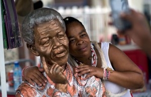 A woman poses with a statue showing South African former president Nelson Mandela as she visits the 'Mandela House' museum in Soweto township in Johannesburg on December 9, 2013.PHOTO: AFP