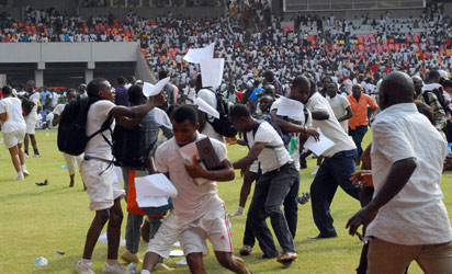 NIGERIA, Abuja : Job-seekers applying for work at the Nigerian immigration department scramble as their exam papers fly in the air, on the pitch of Abuja National Stadium, on March 15, 2014. AFP PHOTO