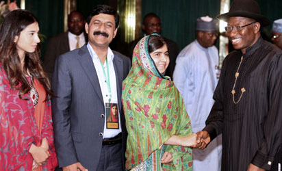 Pakistani education activist Malala Yousafzai (L) watches on July 14, 2014 Nigerian President Goodluck Jonathan look at a book at the State House in Abuja. Malala on July 14 urged Jonathan to meet with parents of the schoolgirls kidnapped three months ago by Boko Haram. Malala, who survived a Taliban assassination attempt in 2012 and has become a champion for access to schooling, was in Abuja on her 17th birthday to mark the somber anniversary of Boko Haram's April 14 abduction of 276 girls from a secondary school in the northeast Nigerian city of Chibok. AFP PHOTO