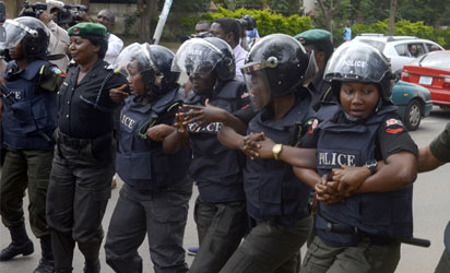 Police officers holds arms to block supporters of 219 schoolgirls kidnapped by Boko Haram militants from marching on the president's official residence in Abuja on October 14, 2014. Some 276 girls were seized from their dormitories at the Government Girls Secondary School in the remote town of Chibok in Borno state, northeastern Nigeria, on the night of April 14. AFP PHOTO