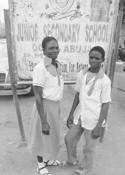 •L-R: Mrs. Juliana Godwin with her son, Sam Godwin, in front of Junior Secondary School, Gosa, Abuja signboard