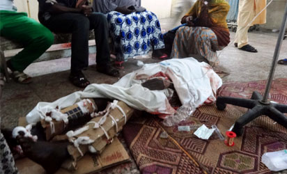 Relatives sit around one of the victims of twin suicide blasts at Kano central mosque in the accident and emergency ward of the Nassarawa Specilist Hospital in northern Nigeria's largest city of Kano on November 28, 2014. At least 120 people were killed and 270 others wounded when two suicide bombers blew themselves up and gunmen opened fire during weekly prayers at the mosque, a week after the emir of Kano, Muhammad Sanusi II, of one of Nigeria's top Islamic leaders called on northerners to defend themselves against Boko Haram Islamists tha have been carrying deadly attacks and seizure of territory in the northeast. AFP PHOTO