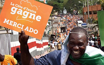 A supporter of Ivorian football national team holds a board reading "Ivory Coast wins, thanks ADO" referring to Ivorian President Alassane Dramane Ouattara as he arrives at the Houphouet Boigny stadium in Abidjan on February 9, 2015, to welcome the players a day after their victory over Ghana in the 2015 African Cup of Nations final. Ivory Coast won 9-8 on penalties after the final ended 0-0 following extra time in Bata, Equatorial Guinea. Since first winning the Cup of Nations in 1992, a lot has been expected from the talented footballers of the cocoa-producing west African country, called "The Elephants". AFP PHOTO/ SIA KAMBOU
