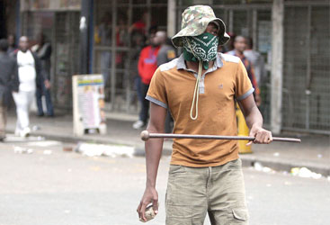 A local resident holds a stone and a traditonal Zulu weapon after a skirmish with foreigners as thousands of people take part in the "peace march" against xenophobia in Durban, South Africa, on April 16, 2015. South African President Jacob Zuma on April 16 appealed for the end of attacks on immigrants as a wave of violence that has left at least six people dead threatened to spread across the country. In the past two weeks, shops and homes owned by Somalis, Ethiopians, Malawians and other immigrants in Durban and surrounding townships have been targeted, forcing families to flee to camps protected by armed guards. AFP PHOTO 
