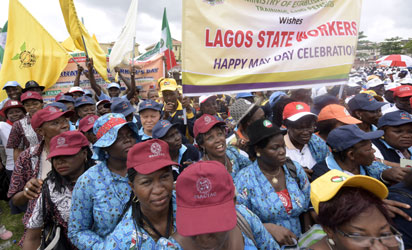 People hold a banner as they march to celebrate Labour Day during a rally in Lagos on May 1, 2015. Tens of thousands of people across the globe were hitting the streets on May 1 for mass rallies marking International Labour Day. AFP PHOTO