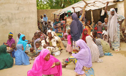 This handout picture released by the Nigerian army on April 30, 2015 and taken this week in an undisclosed location in the Sambisa Forest, Borno state, purportedly shows a member of the Nigerian Army standing next to a group of women and children rescued in an operation against the Islamist group Boko Haram. Boko Haram hostages were held in atrocious conditions in the group's Sambisa Forest stronghold, Nigeria's military said on April 30 after nearly 500 women and girls were released this week. AFP PHOTO / NIGERIAN ARMY