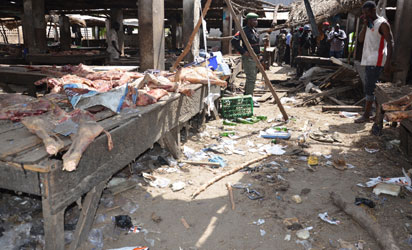 Nigerian police and civilians inspect the site of a suicide attack at a busy cattle market in the northeastern Nigerian city of Maiduguri on June 2, 2015. At least 13 people were killed in the attack, the Red Cross and civilian vigilantes battling Boko Haram said. The blast in the Borno state capital happened as traders were wrapping up business for the day. AFP PHOTO