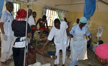 Medical staff help a man who is treated in a hospital after he was injured in a bomb blast carried out by young female suicide bomber detonated her explosives at a bus station in Maiduguri, northeast Nigeria, on June 22, 2015 in an attack likely to be blamed on Boko Haram.  The blast happened near a fish market in the Baga Road area of the city, which has been repeatedly targeted in recent weeks by shelling, bombs and suicide attacks.  AFP PHOTO