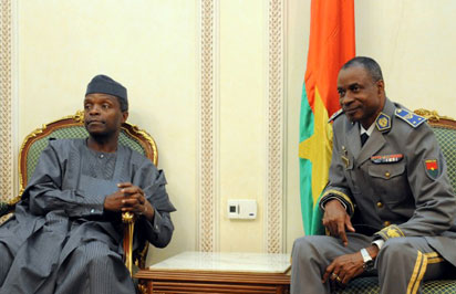 Nigeria's Vice-President Yemi Osinbajo (L) is welcomed by Bukina Faso's coup leader General Gilbert Diendere (R), on September 23, 2015 at Ouagadougou International airport as six leaders of the Economic Community of West African States (ECOWAS) arrive to oversee the formal re-installation of interim President Michel Kafando and to try and sort out two contentious issues : an amnesty plan for the putschists and whether upcoming elections should be open to supporters of previously deposed veteran dictator Blaise Compaore. Burkina Faso's Kafando said he has resumed his duties a week after being overthrown in a coup by the west African country's presidential guard. AFP PHOTO / AHMED OUOBA