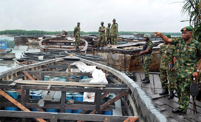 OIL THEFT —Commander, 2 Brigade, Nigerian Army, Port Harcourt, Brig.-Gen. Stevenson Olabanji (right) and other officers, during a raid on an illegal oil bunkering site discovered on Nigerian Ports Authority Road in Port Harcourt, Tuesday. Inset: About 5,150 drums containing illegally refined diesel discovered during the raid. Photos: NAN.
