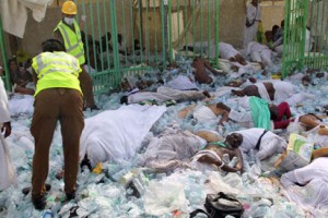 Saudi emergency personnel stand near bodies of Hajj pilgrims at the site where at least 717 were killed and hundreds wounded in a stampede in Mina, near the holy city of Mecca, at the annual hajj in Saudi Arabia on September 24, 2015. The stampede, the second deadly accident to strike the pilgrims this year, broke out during the symbolic stoning of the devil ritual, the Saudi civil defence service said. AFP PHOTO / STR