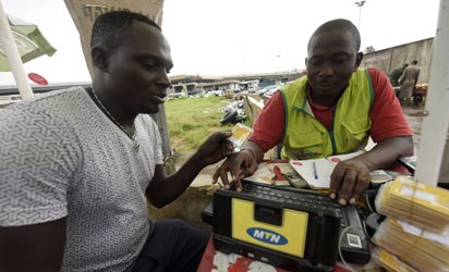 A MTN service provider tries to register a client's SIM card in Lagos, on October 27, 2015. Nigeria's telecommunications regulator has fined South African mobile giant MTN $5.2 billion for missing a deadline to disconnect unregistered SIM cards, the company announced on Monday. The penalty saw shares in Africa's largest telecommunications company crash more than 12 percent to 167 rand on the Johannesburg Stock Exchange, the biggest fall the firm has suffered in a day since November 1998. AFP PHOTO