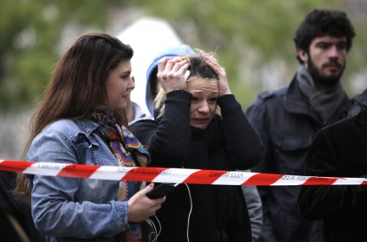 A woman reacts as she looks at the flowers and messages left at a rail cordon close to the Bataclan theatre in the 11th district of Paris on November 14, 2015, the day after a series of attack on the city resulting in the deaths of more than 128 individuals. Some 80 people were gunned down at the Bataclan theatre in Paris late November 13, during a concert by the US band Eagles of Death Metal. AFP PHOTO / KENZO TRIBOUILLARD