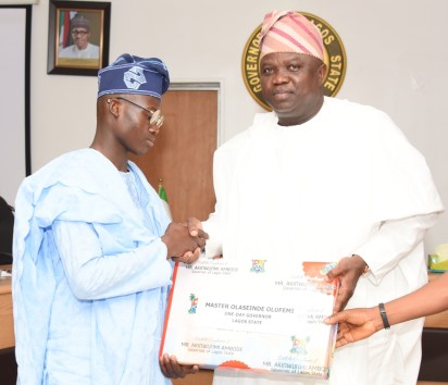 Lagos State Governor, Mr. Akinwunmi Ambode (right), presenting a gift to the Winner of 2016 Spelling Bee Competition and One-Day Governor, Master Olaseinde Olufemi of Shasha Community Senior High School (left) during the 2016 One-Day Governor’s visit, at the Exco Chambers, Lagos House, Ikeja, on Friday, July 08, 2016.(File)